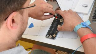 Personne en train de réparer un smartphone démonté lors d'un atelier de réparation