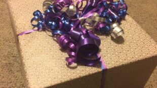 Cadeau emballé dans du papier uni avec un ruban violet frisé